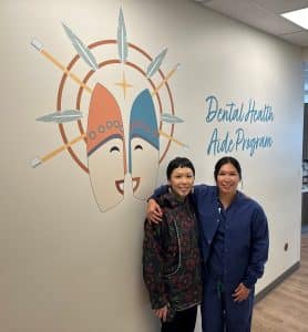 Leandra Beech and Mek Apangalook standing in front of Dental health Aide Program Mural